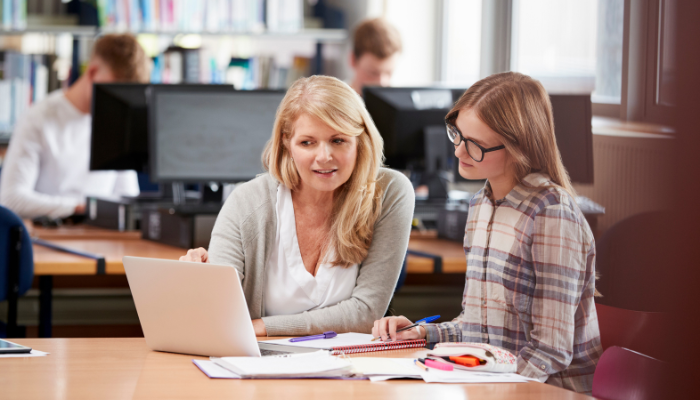 Teacher explaining something on laptop to student