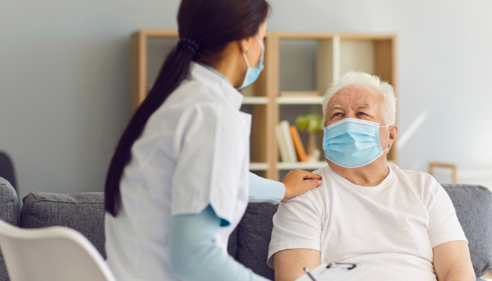 Doctor wearing mask talking to older COVID patient wearing mask.