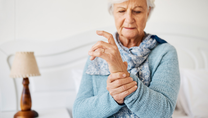 Older woman holding wrist with joint pain