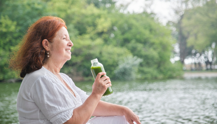 Woman sitting outside drinking green detox juice at retreat