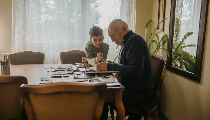 Older man and grandchild looking at photos at dining table