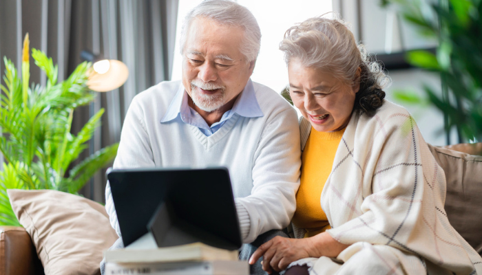 Asian senior couple smiling on computer together