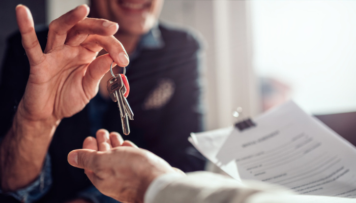 Man handing another man keys to a house