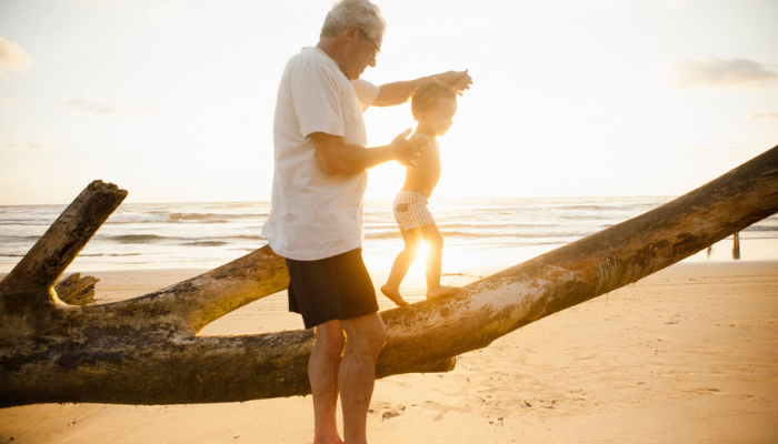 Older man and child on beach traveling with Grandchildren