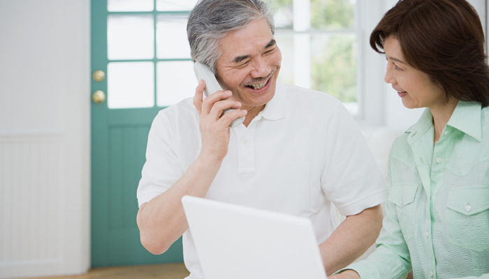 Happy Asian couple on their cordless home phone