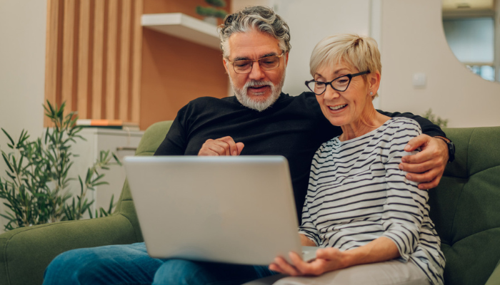 Couple smiling while on laptop together at home