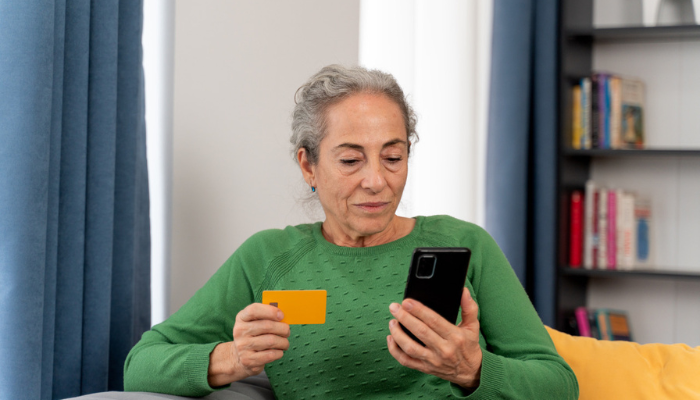 Woman looking at her phone and Medicare flex card.