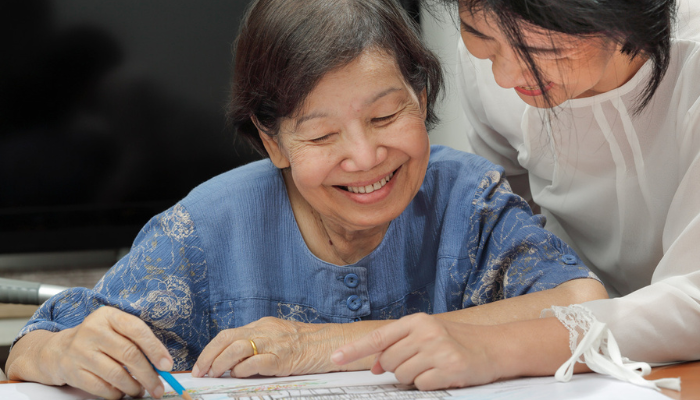 Elderly Asian woman drawing for senior art therapy.