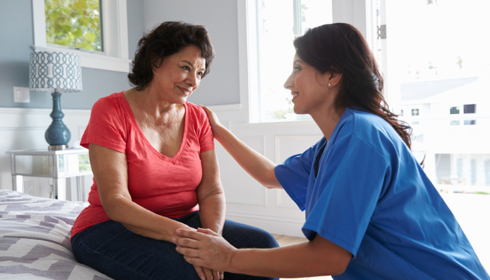 Woman talking to a nurse in her bedroom.