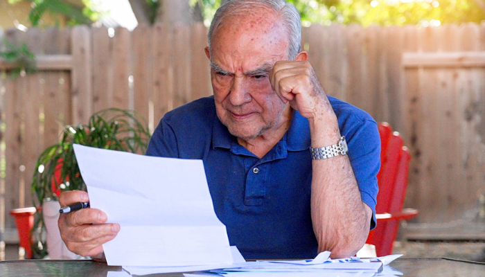 Older man reviewing paperwork outside.