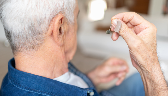 Older man putting a hearing aid in.