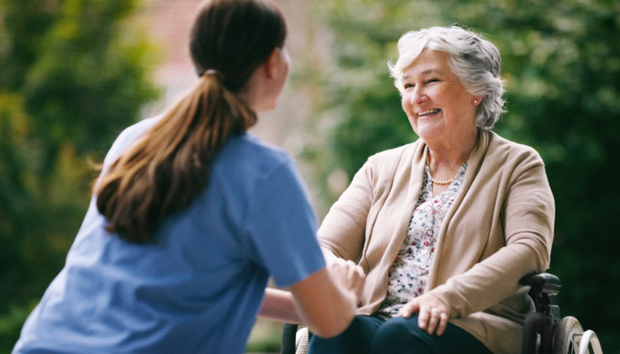 Disabled woman in wheelchair speaks to home health nurse.