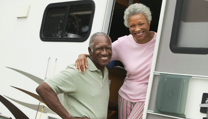 Older African American couple smiling outside of their RV.