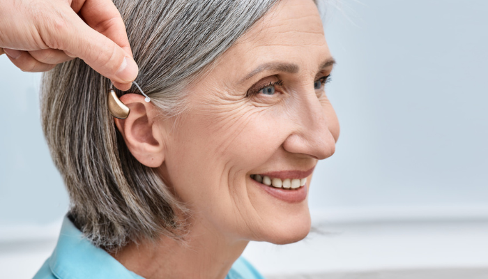 Older woman using a hearing aid.