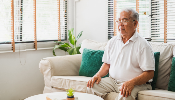 Senior Asian man enjoying a relaxing sound bath on the couch.