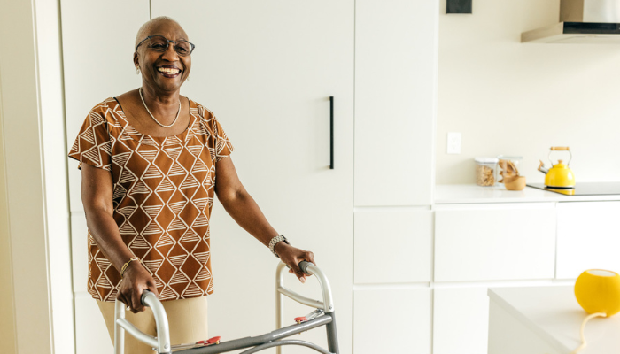 Happy African American senior woman smiling while using her walker at home.