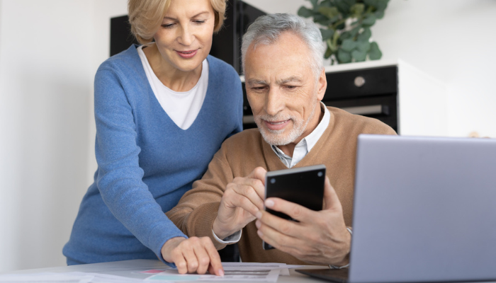 Senior couple reviewing banking information on laptop together.