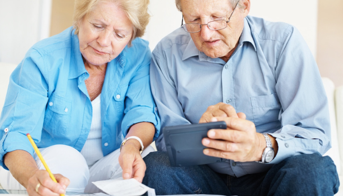 Senior couple reading iPad and making notes together.