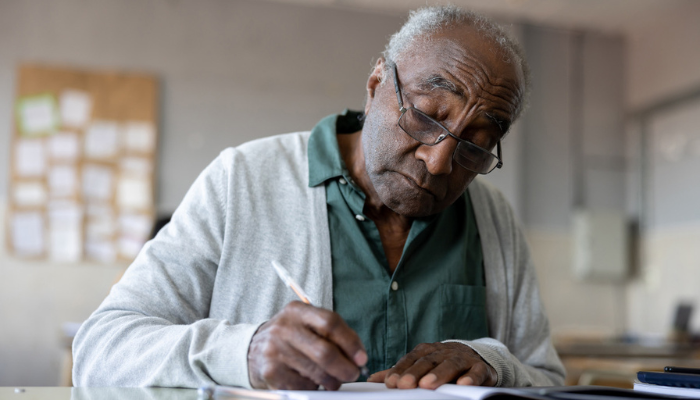 Older African American man thoughtfully writing a story.