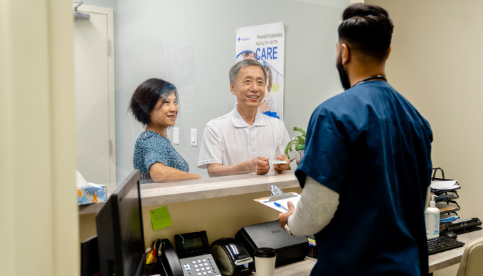 Older Asian couple speaking to a nurse.