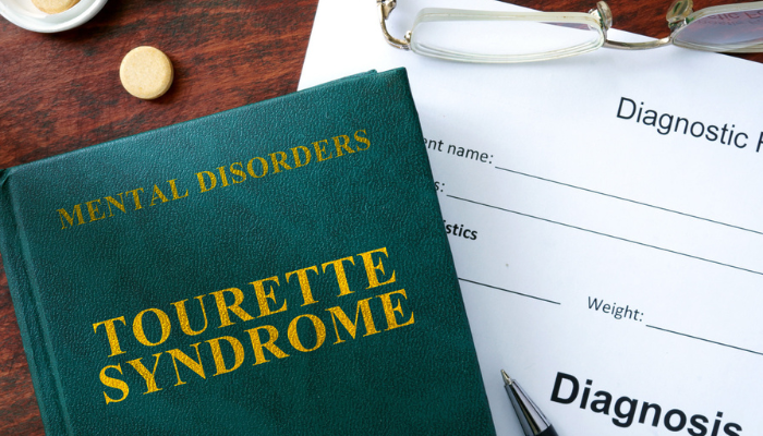 Tourette Syndrome written on a medical book with paperwork.