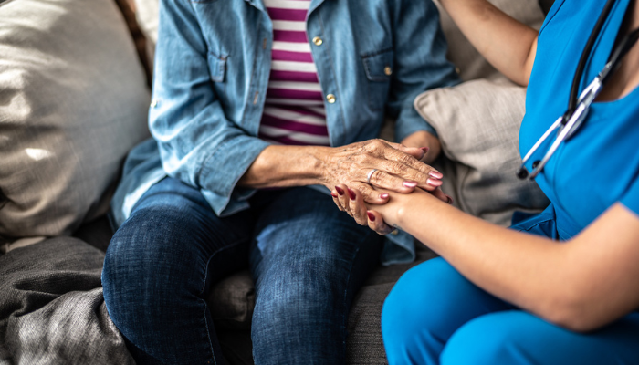 Older woman holding hand of nurse.