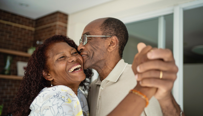 Older African American couple dancing and laughing together.