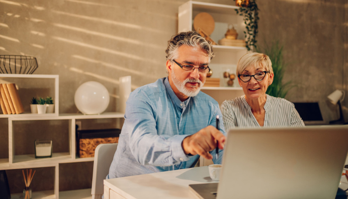 Older man and woman looking at laptop together.