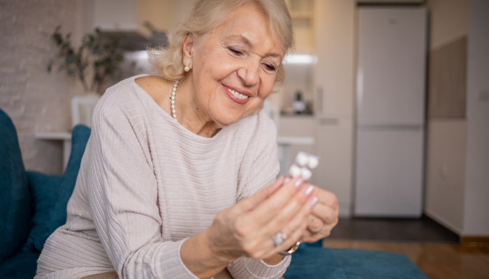 Senior woman reading probiotic in her kitchen.