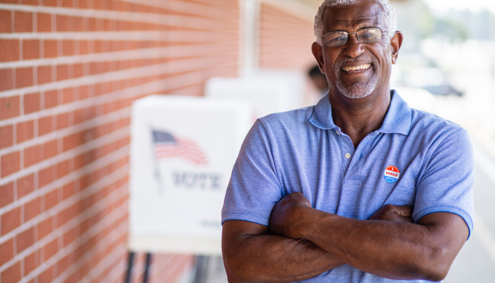Older African American man standing outside of voting area.