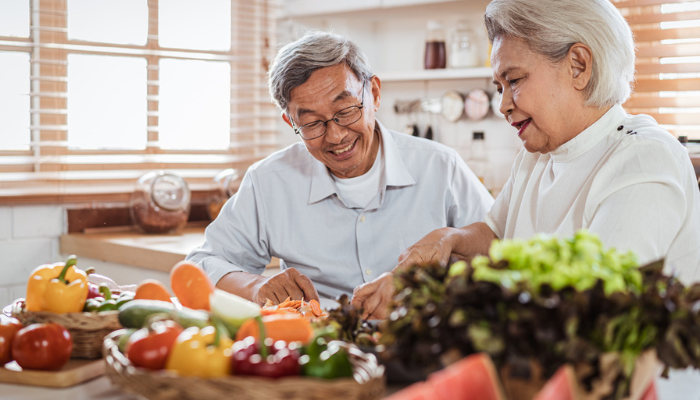 Senior Asian couple prepping dinner together in the kitchen.