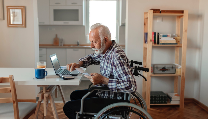 Older man in wheelchair paying bills online.
