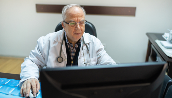 Doctor reviewing medical device information on his computer.