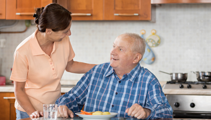 Senior man being served food by woman at home.