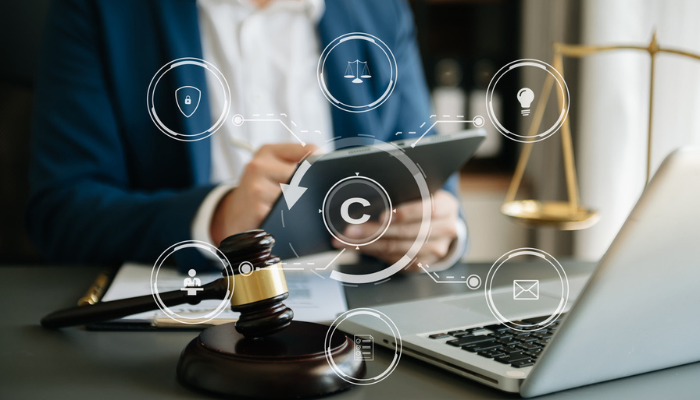 Legal icons on image of lawyer reviewing documents on laptop.