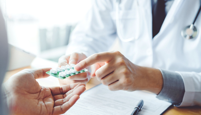 Doctor holding pills handing to patient.