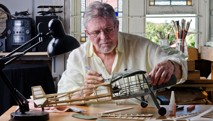 Older man working on model airplane.