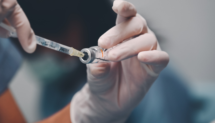 Doctor using a syringe to get shingles vaccine out of vial.