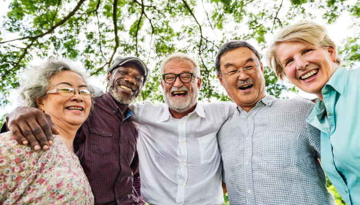 Happy group of diverse senior friends smiling outside.